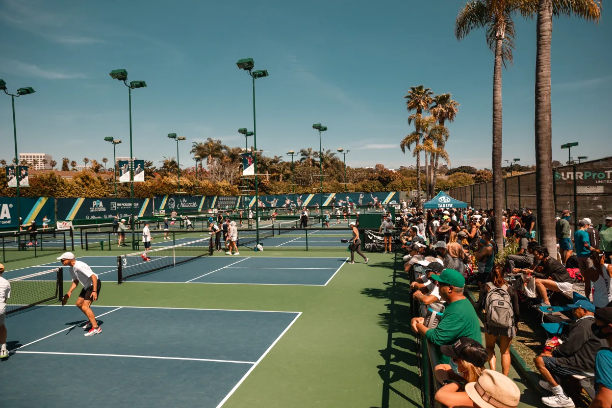 Players and spectators beside outdoor pickleball courts at the 2021 Newport Beach Doubles Shootout
