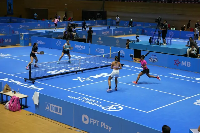 Players compete on a blue indoor pickleball court